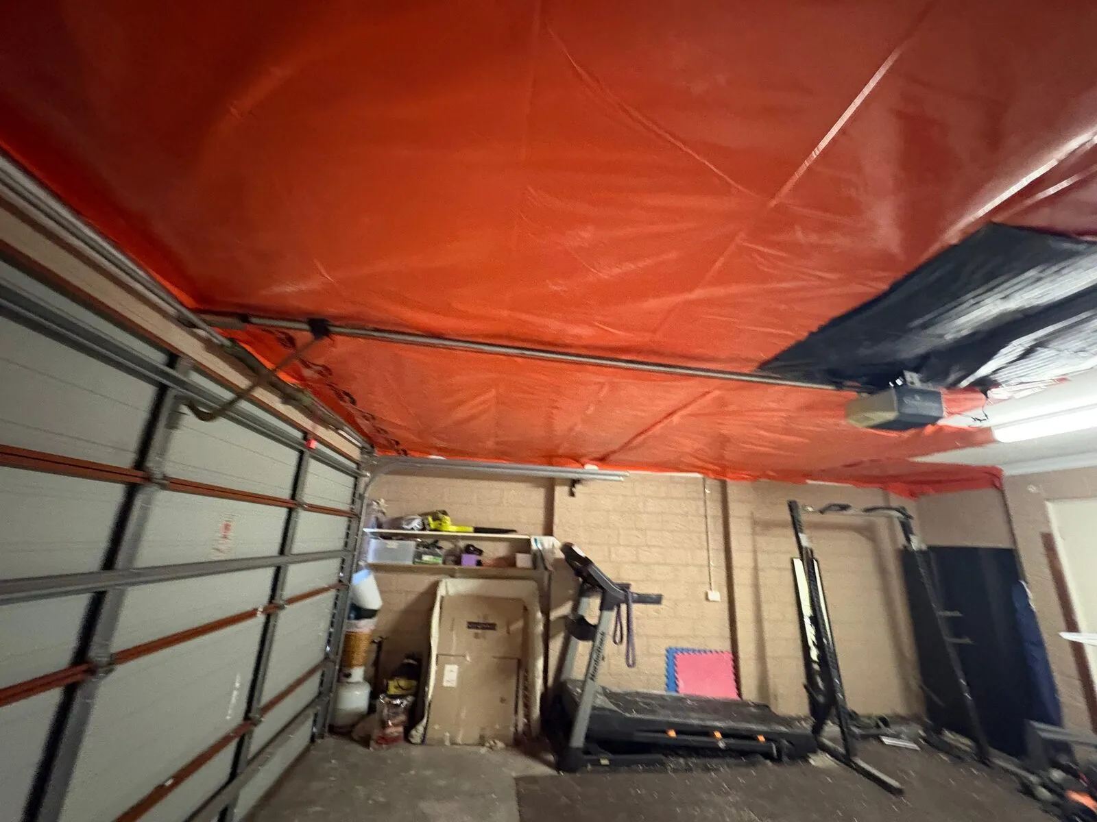 Temporary sheeting fixed across a garage ceiling after make-safe