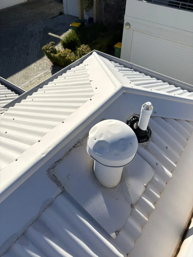 Roof ventilator and penetration flashing on a corrugated metal roof